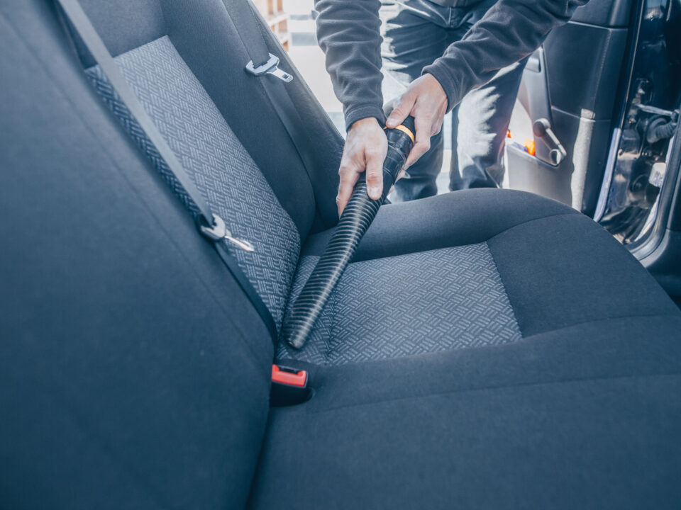 a man cleaning and vacuuming the interior of a car