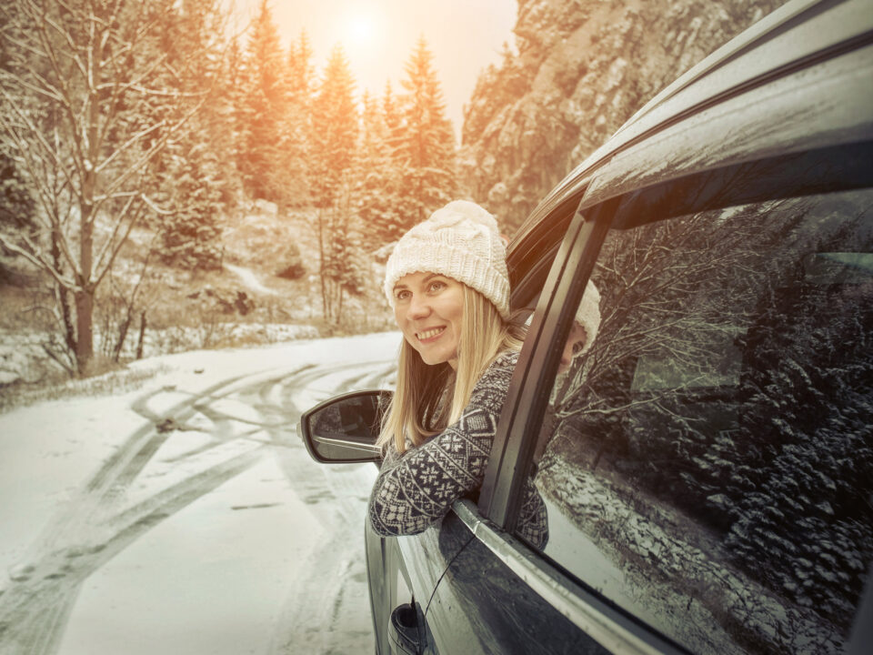a young woman driving her car in the snow