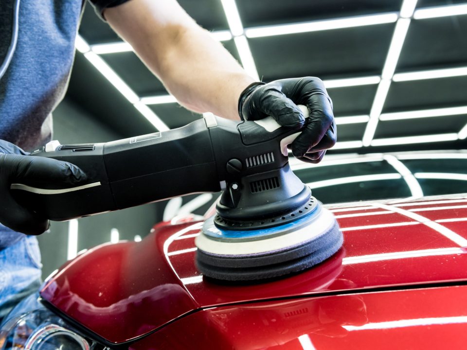Auto detailer polishes a car with an orbital polisher